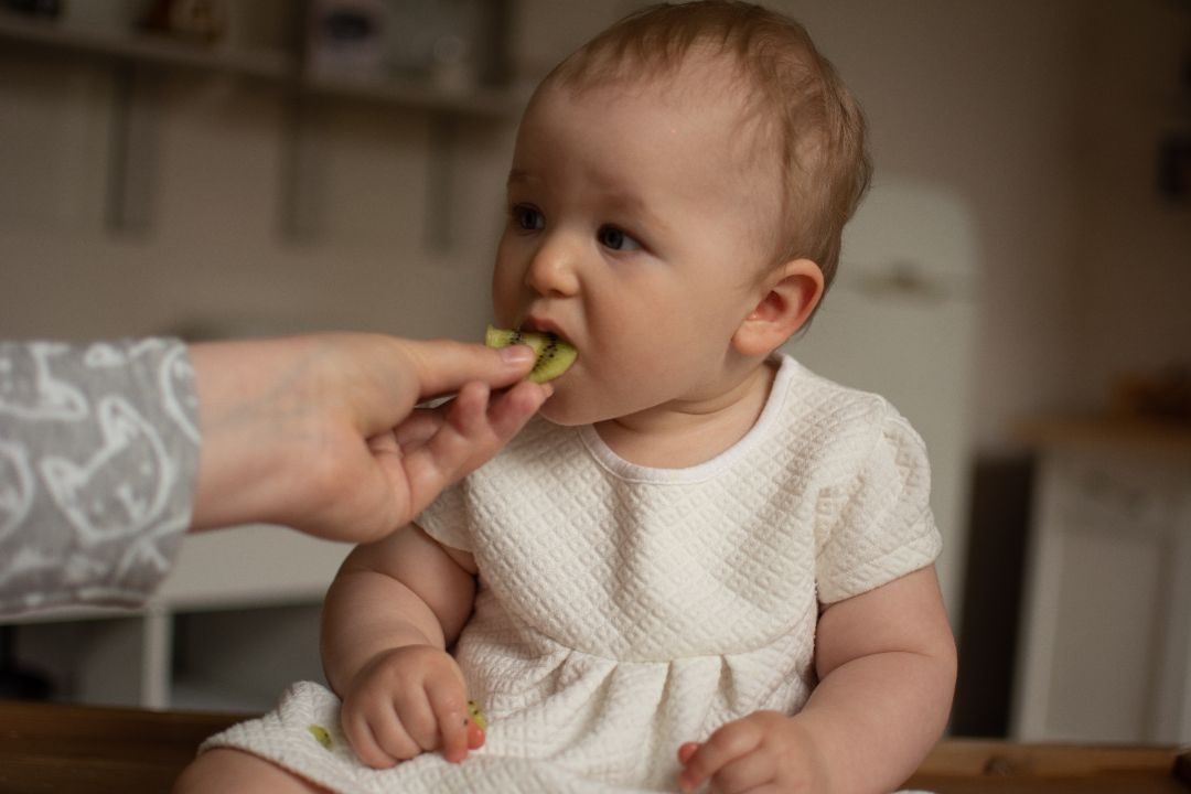 A baby being offered a piece of food by hand